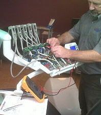 Technician working on electronic cables and components with a multimeter nearby.